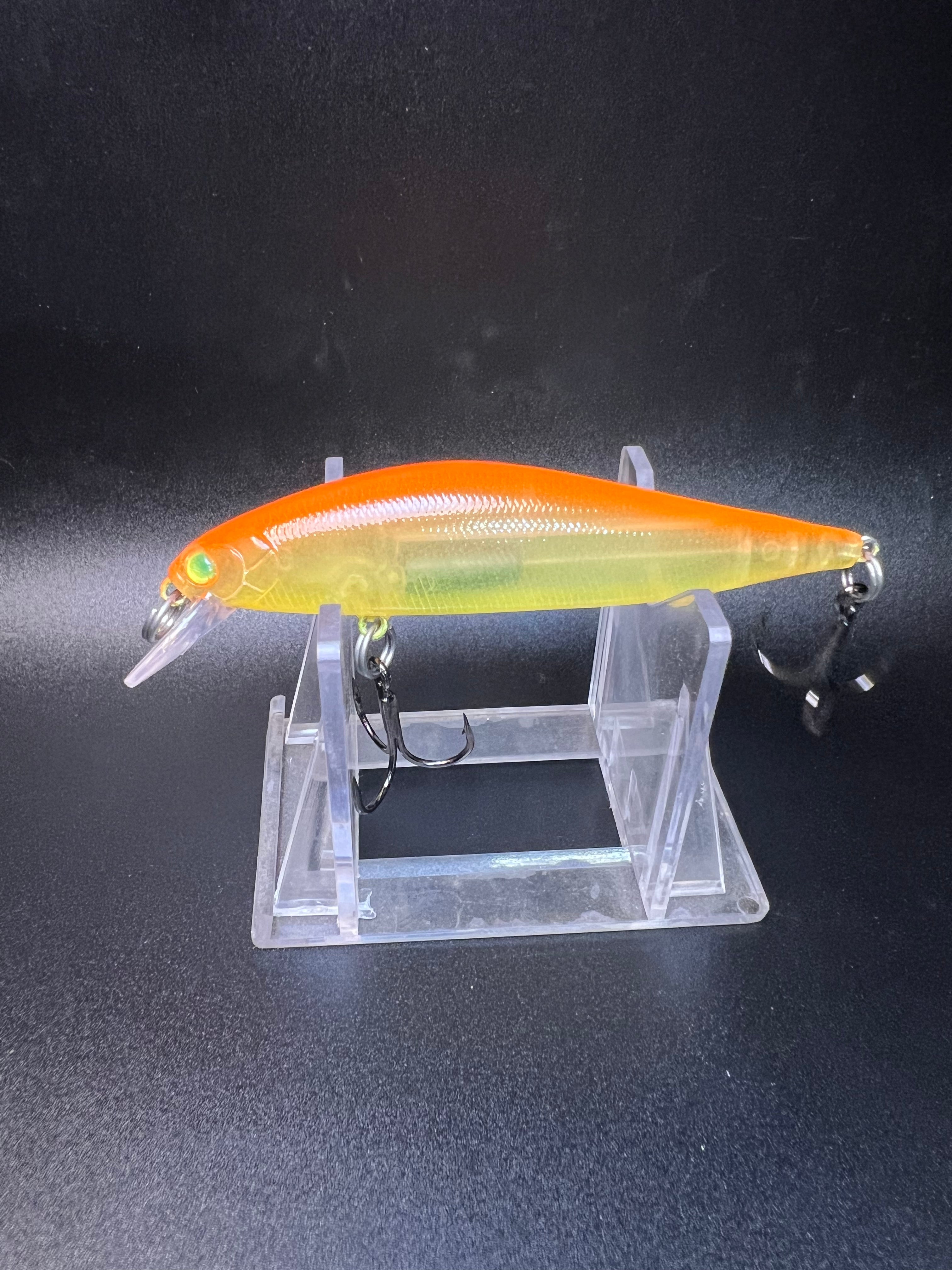 Orange-top yellow jerk bait with lip and treble hooks on clear stand