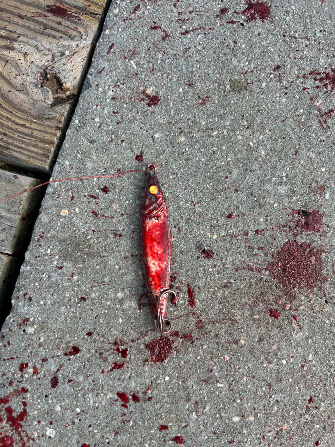 Red-and-white jigging spoon lure with yellow eye and two treble hooks