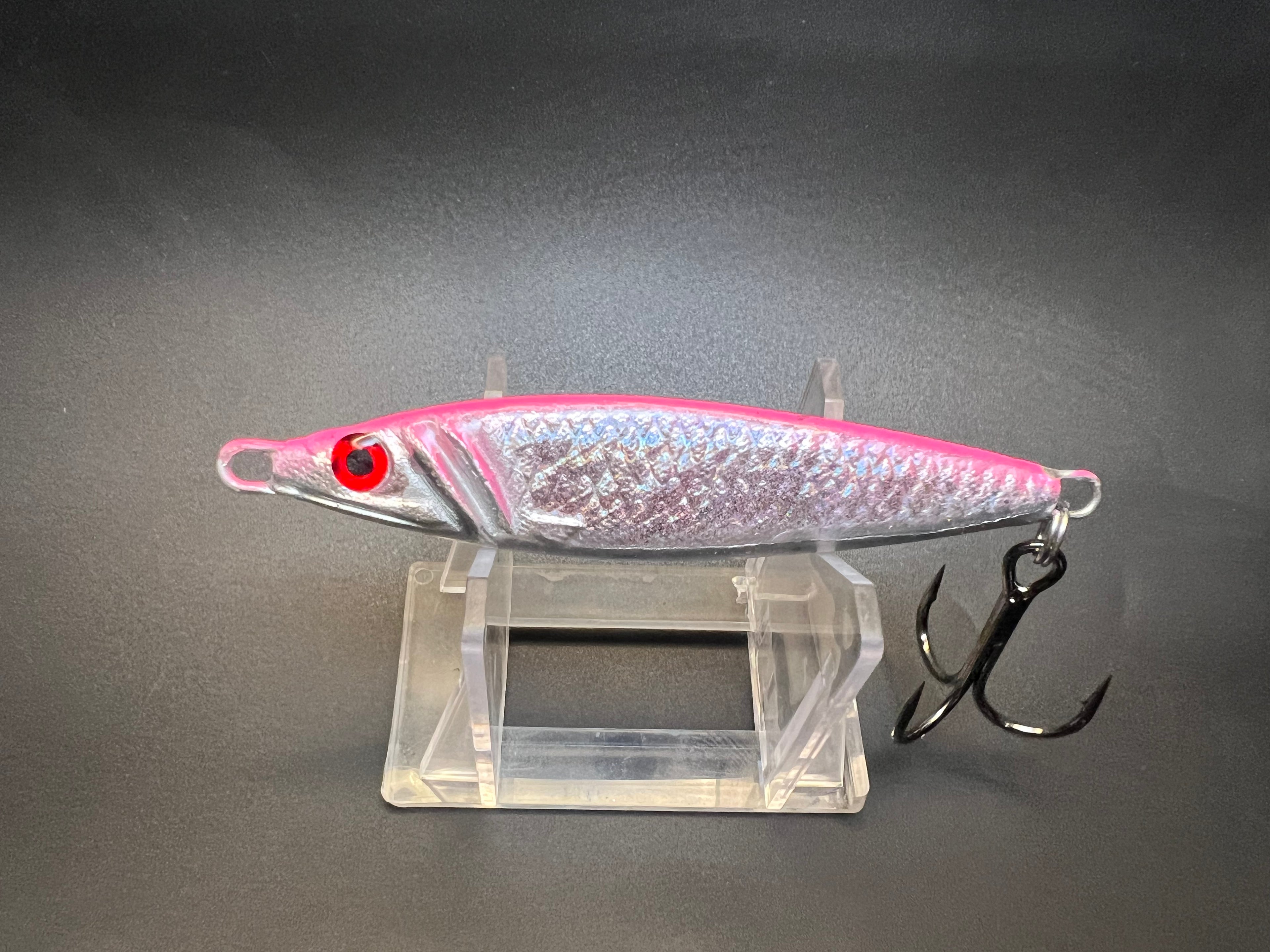 Jigging spoon lure with pink and silver metallic body, red eye, two treble hooks