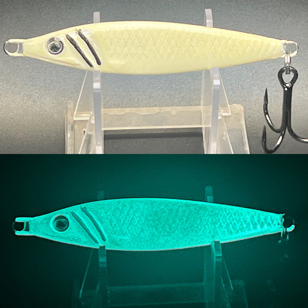 UV glow jigging spoon with pale yellow body and black stripes, on a display stand