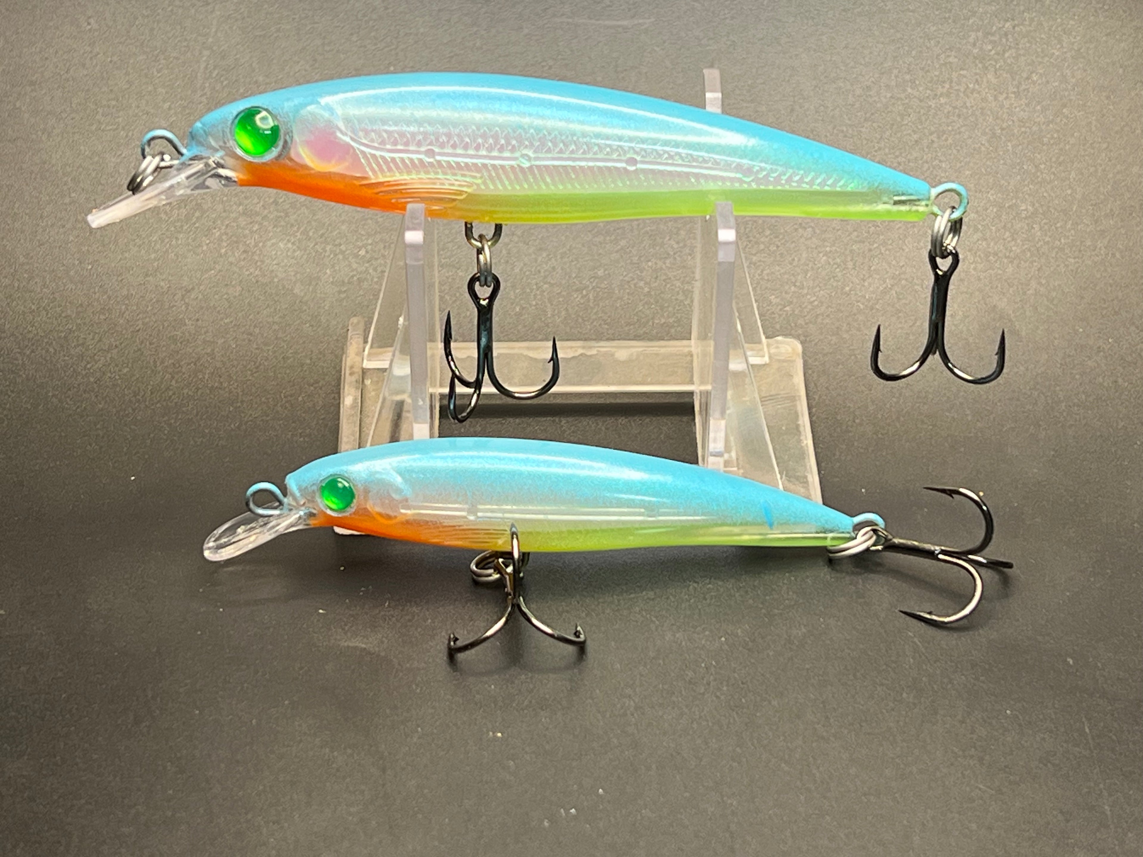 Fishing minnow lures with treble hooks, teal-blue body and orange belly.