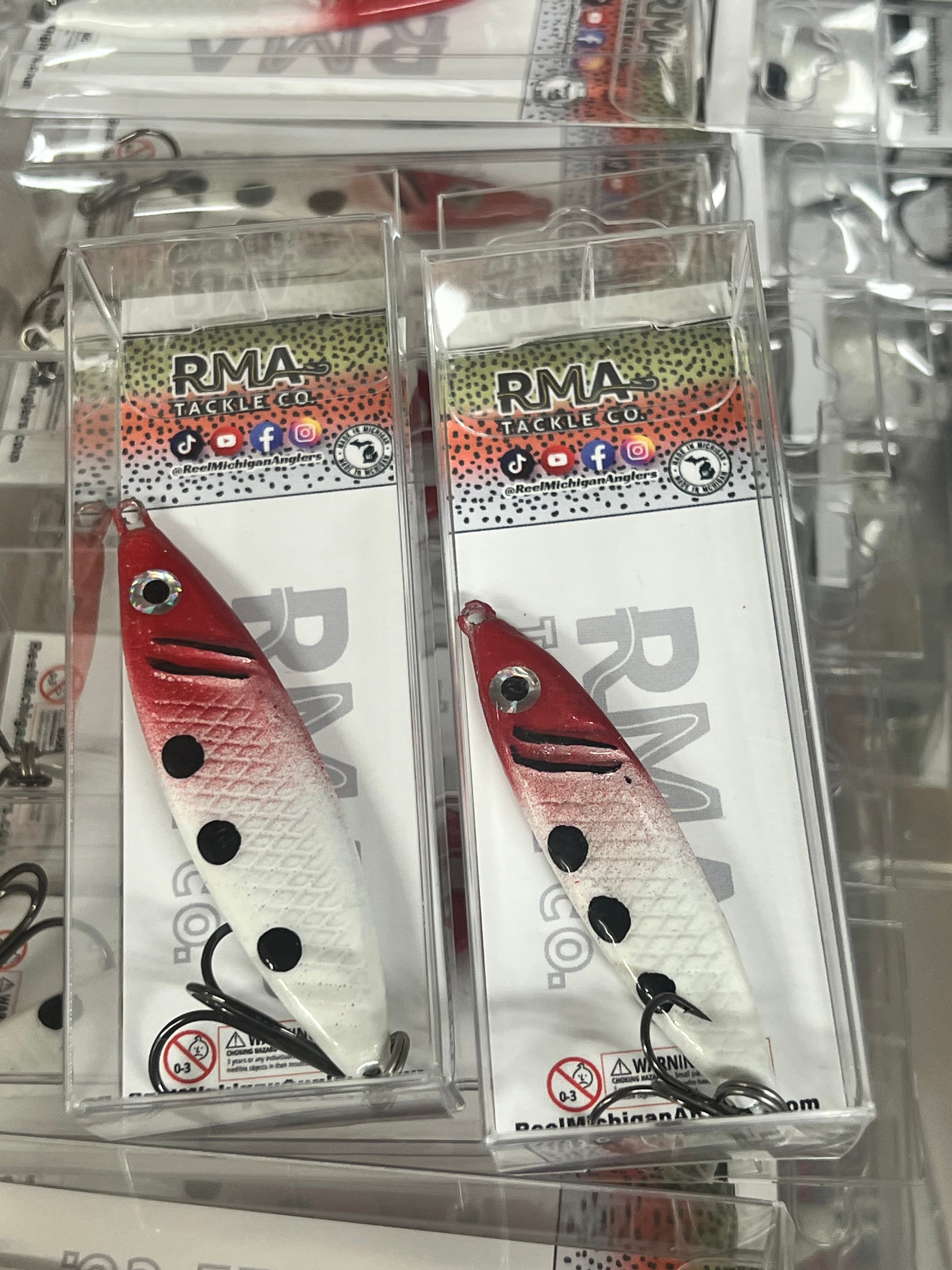 Red and white fishing jigging spoon lure with black spots, in blister pack