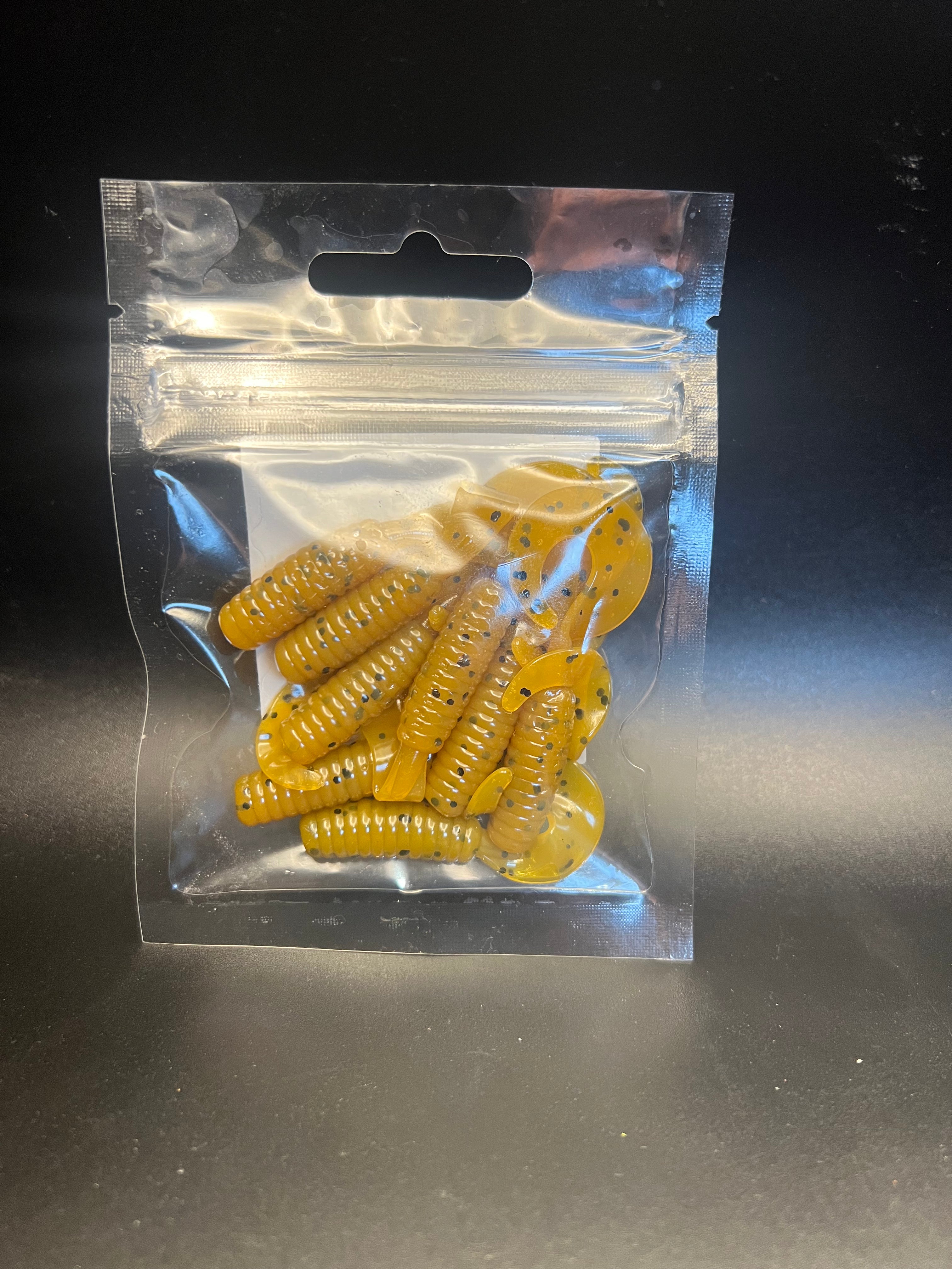 Yellow curly twister tail grub soft plastics with darker speckles in clear bag