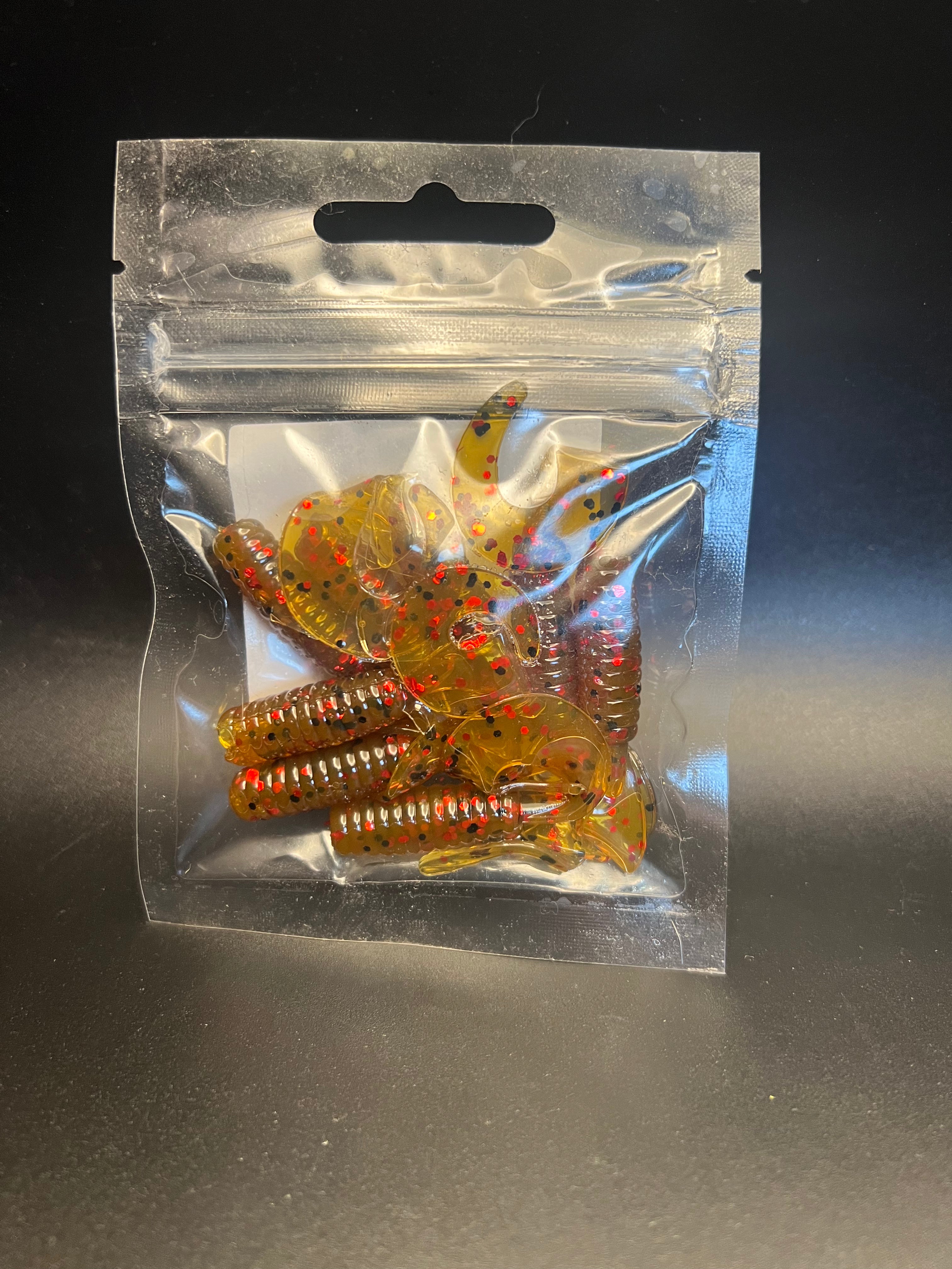 Amber-gold curly twister tail grubs with red speckles in clear bag