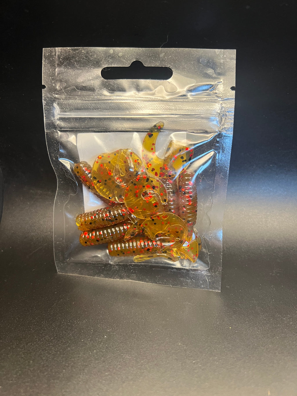 Gold gravy-style curly twister tail grubs with red speckles in clear bag