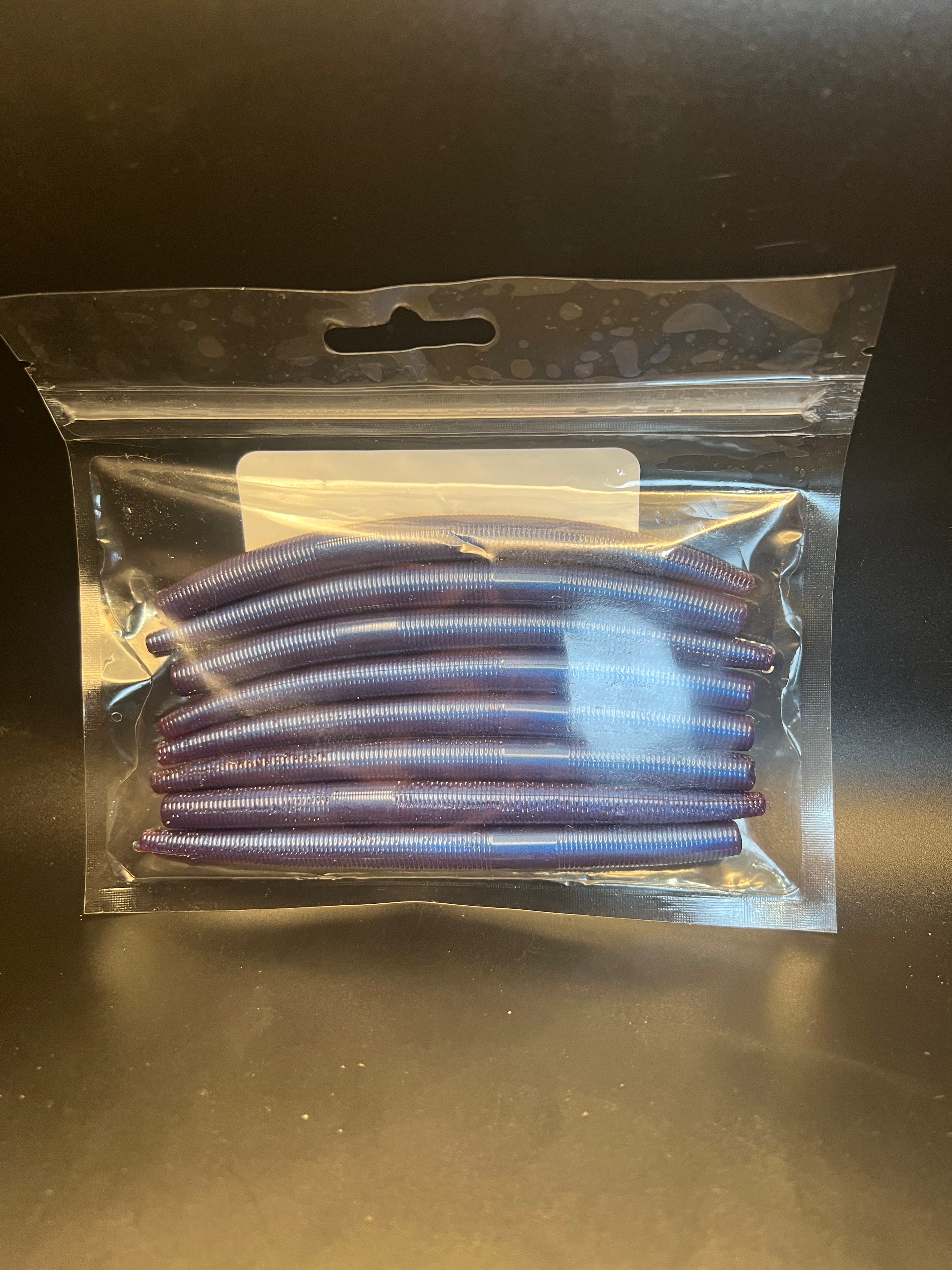 Soft plastic stickbait worms in blue-violet color inside clear blister pack