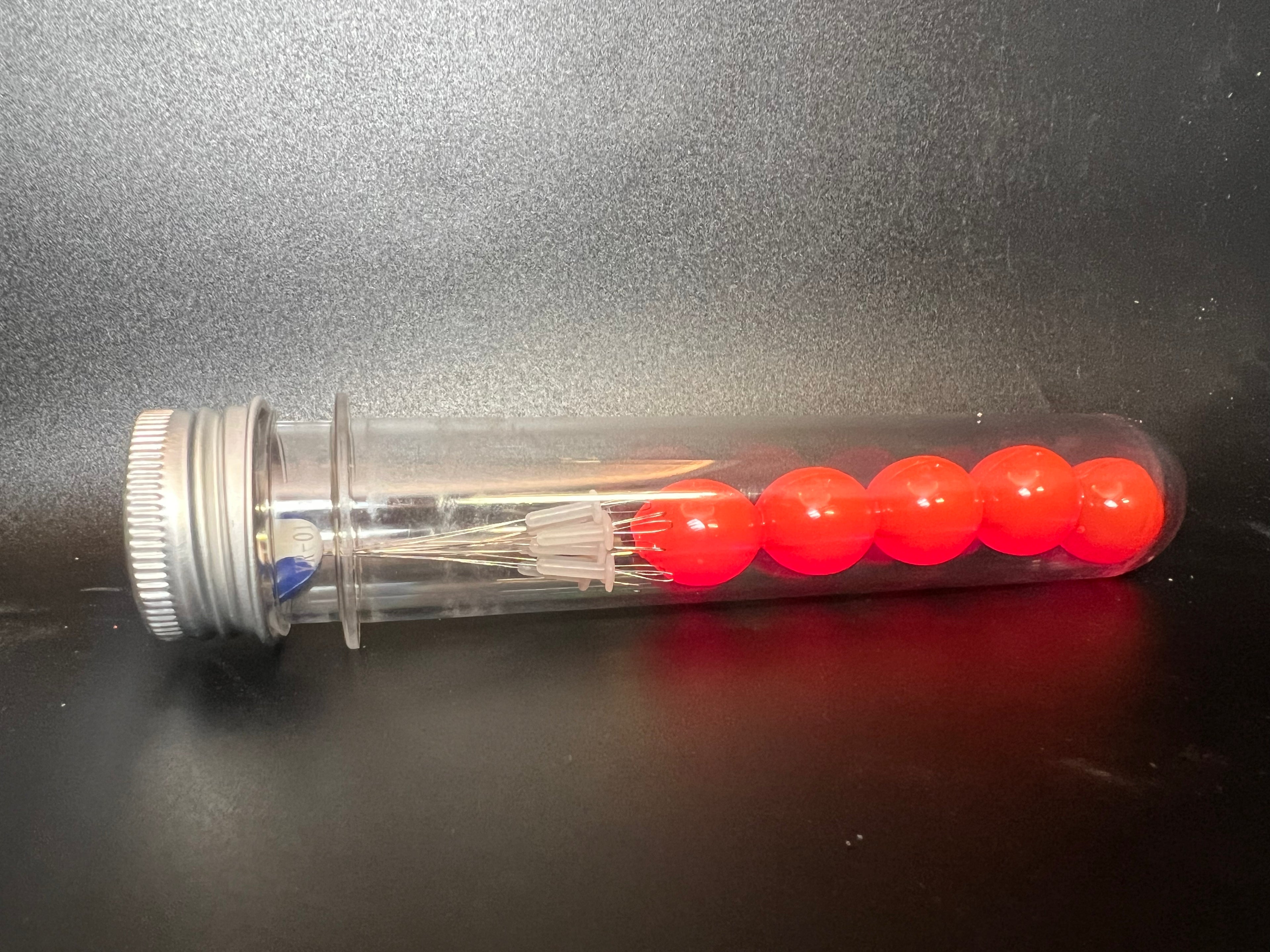 Red soft plastic fishing beads in clear dispensing tube
