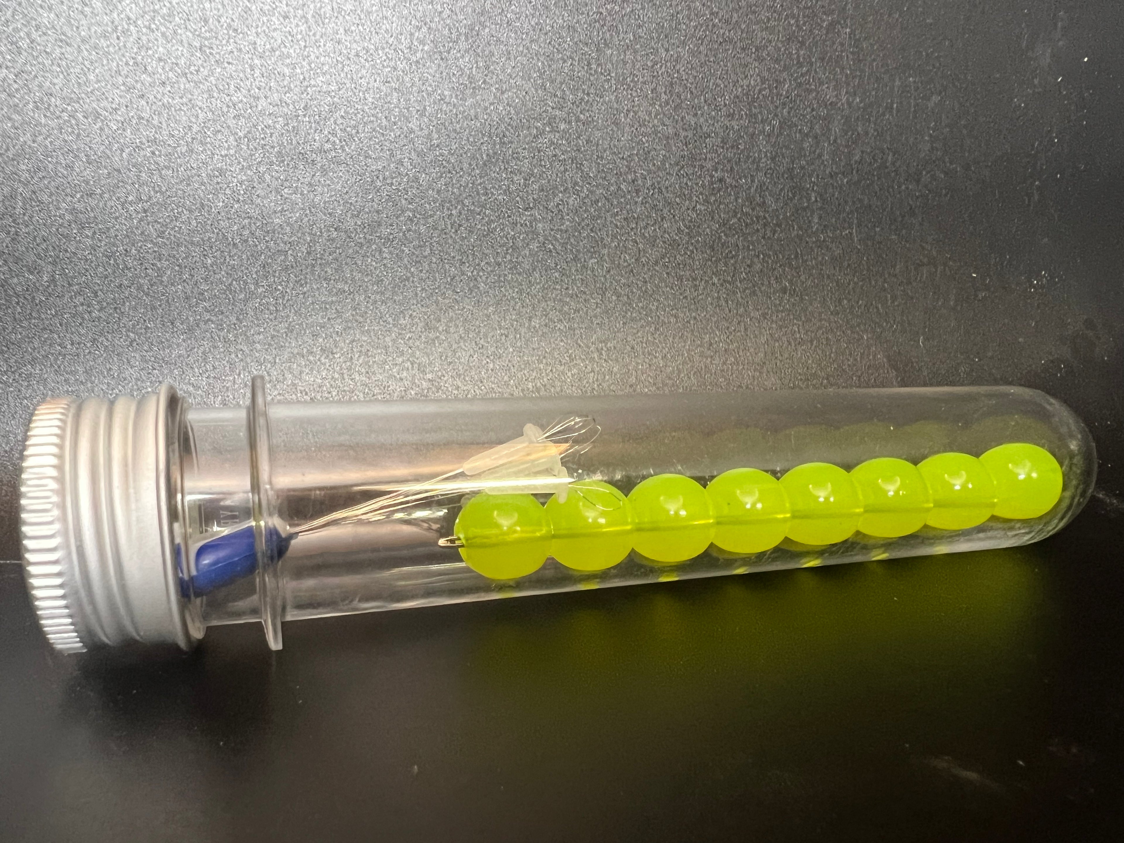 Yellow soft plastic beads in clear dispenser tube for salmon & steelhead fishing