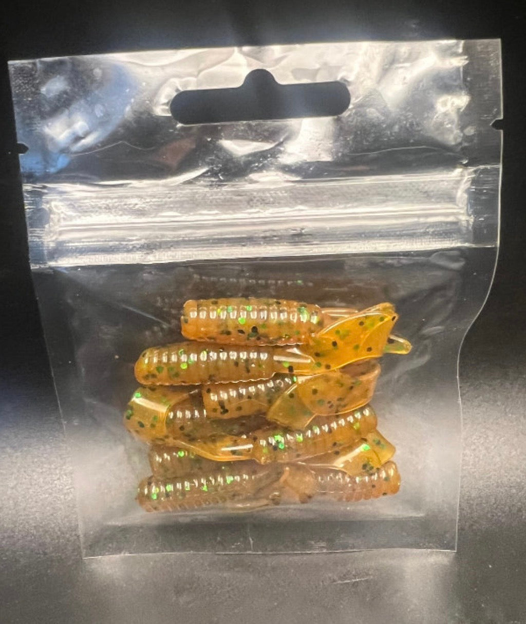 Curly Twister Tail grub soft plastic lure, amber with green speckles, in sealed bag