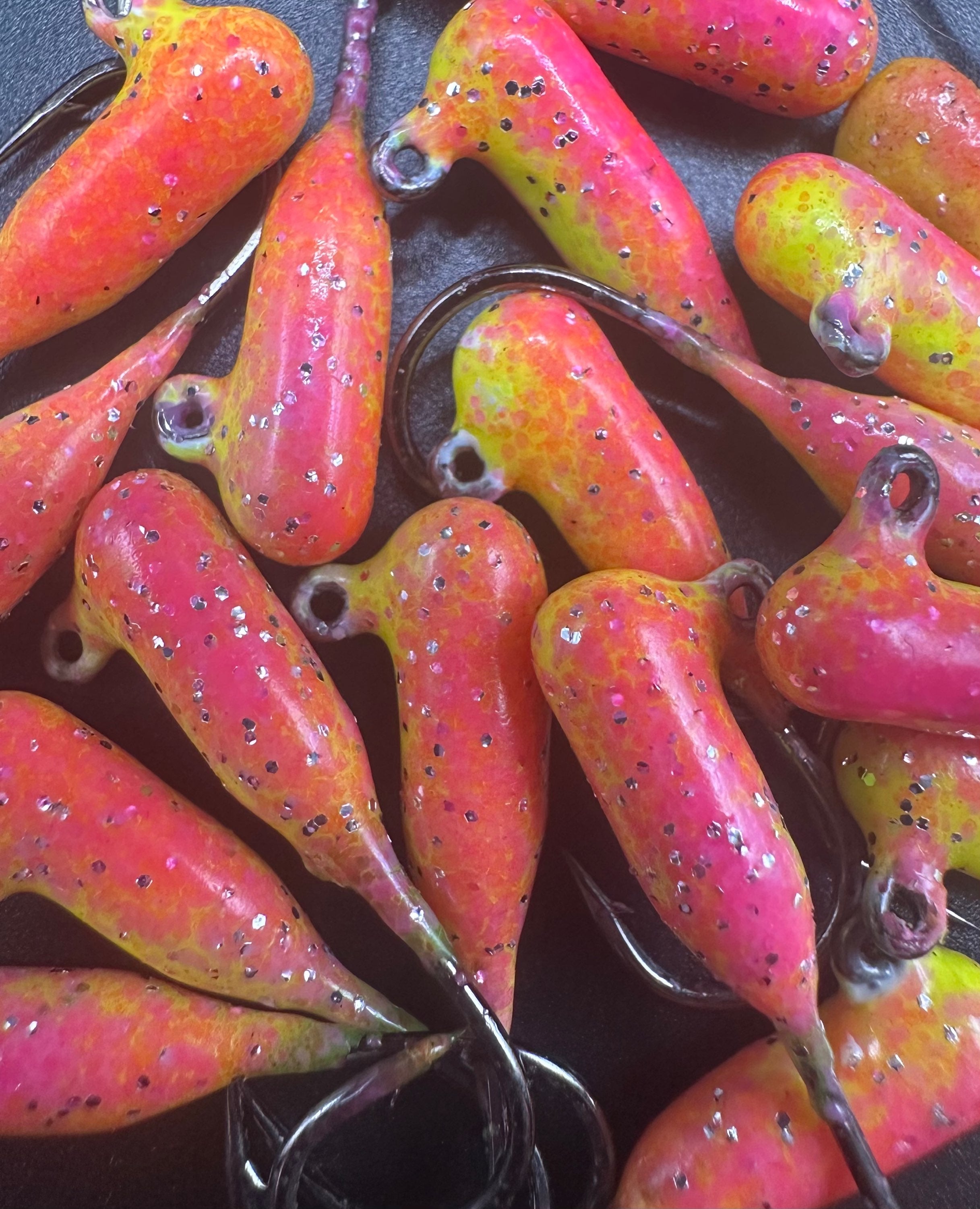 Colorful rainbow tube jigs, pink-orange with speckles, visible metal hooks