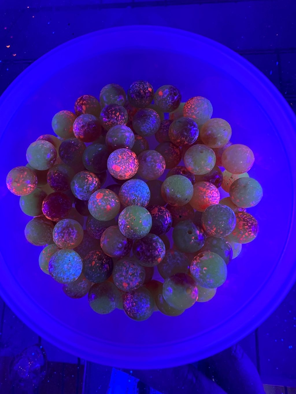 Round glass fishing beads with purple-blue speckled finish, in a bowl