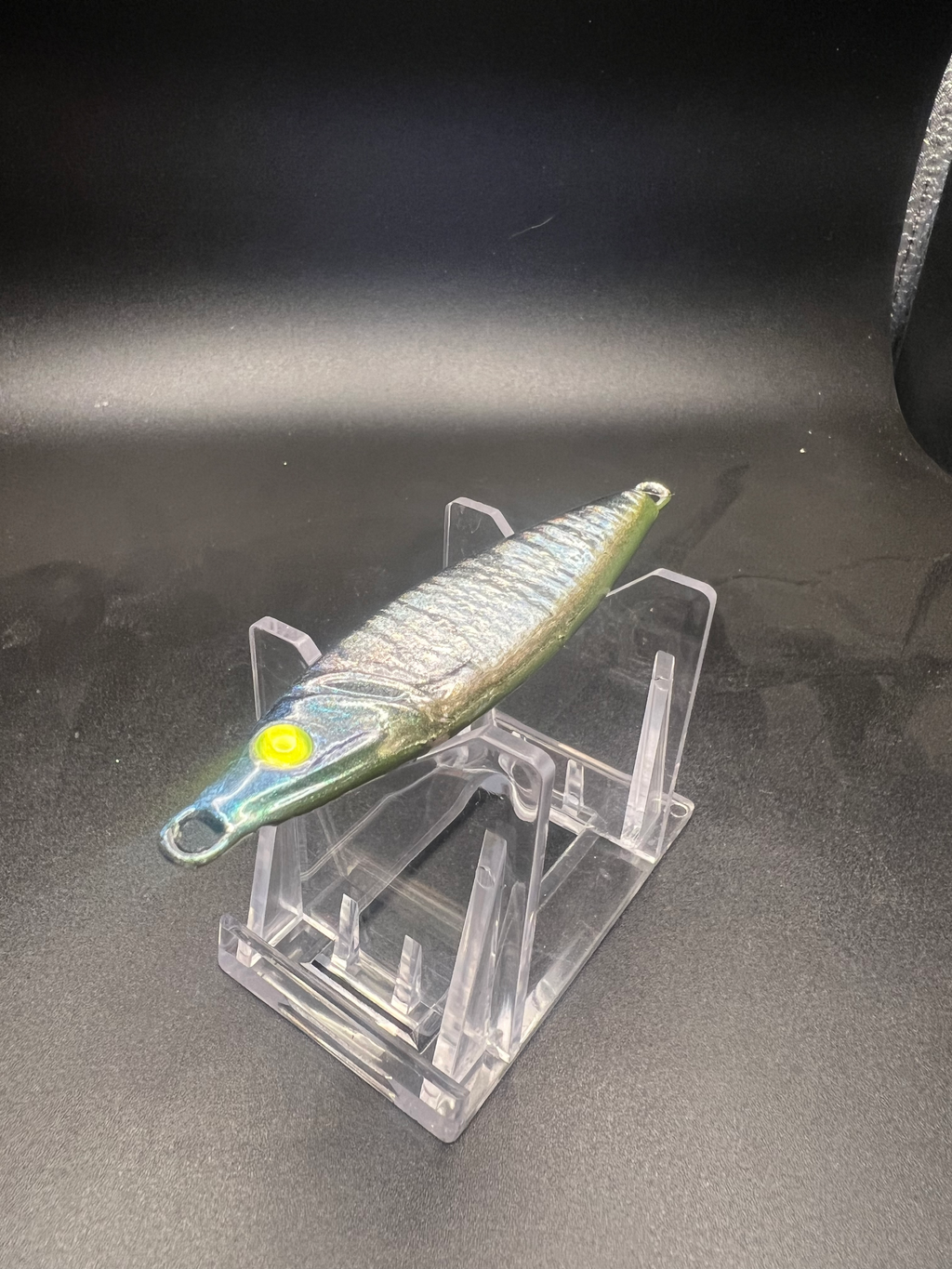UV 2 oz jigging spoon with metallic green body, yellow eye, and side treble hook