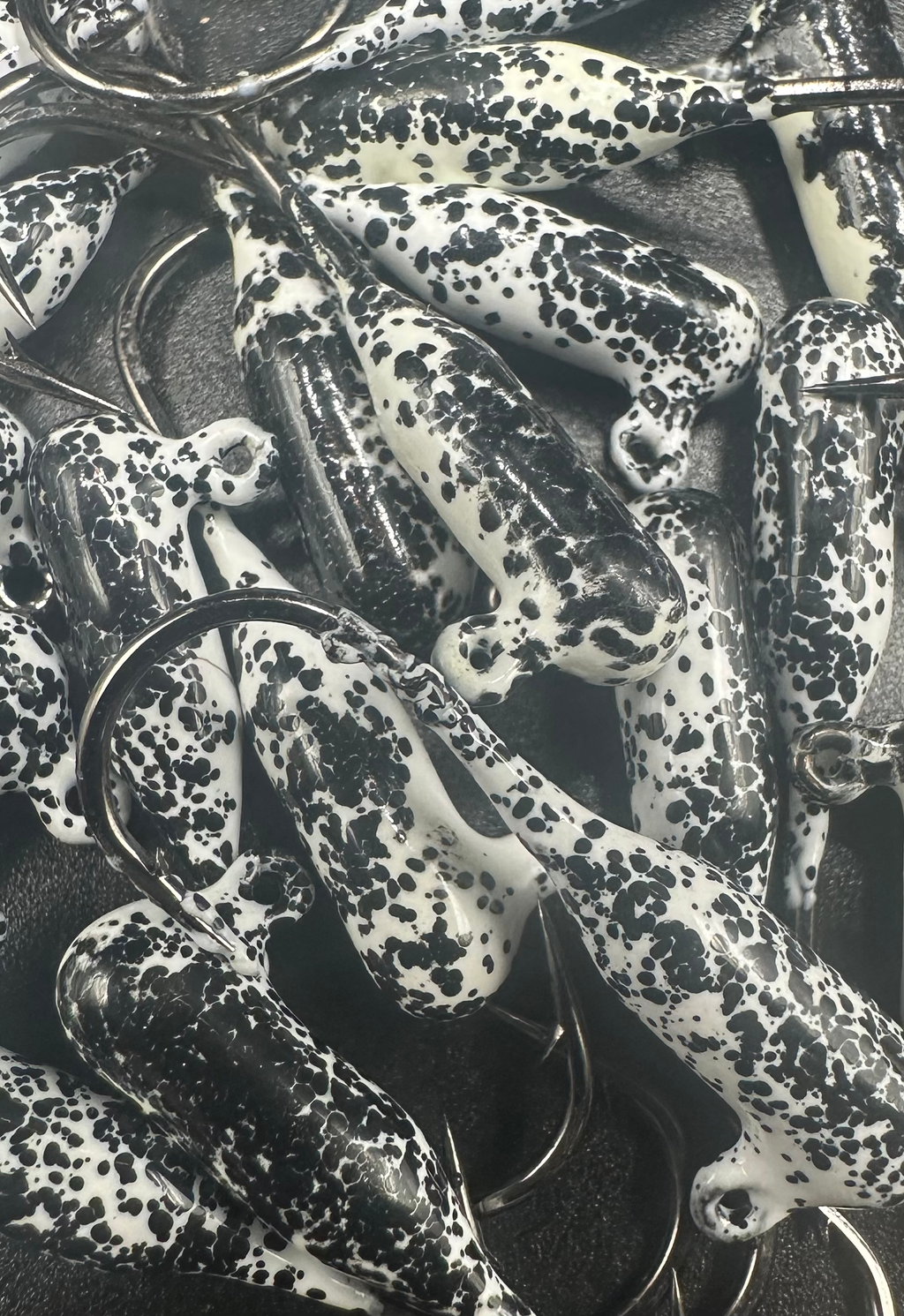 White-and-black speckled steelhead tube jigs with wire hooks, close-up