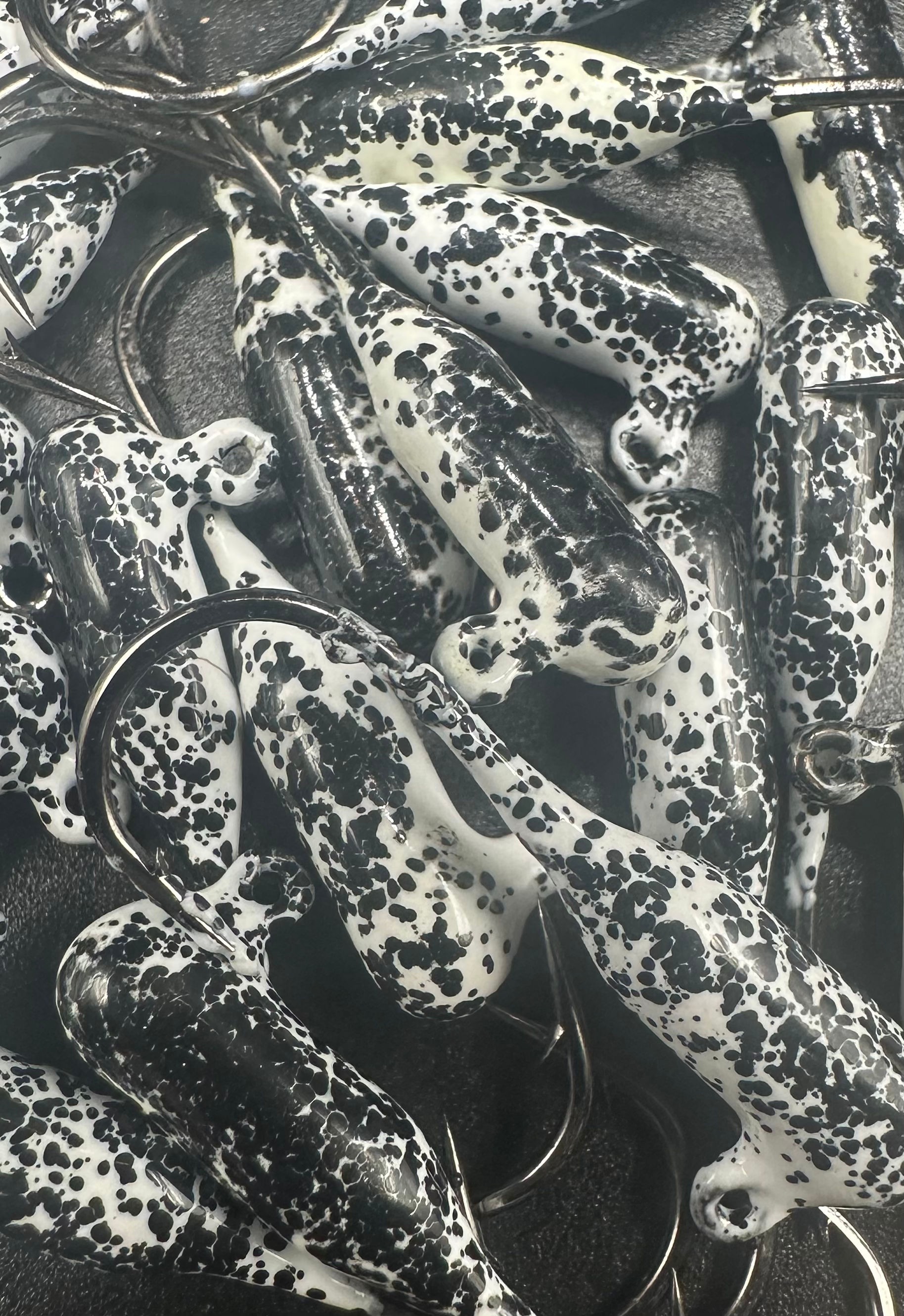 White-and-black speckled steelhead tube jigs with wire hooks, close-up