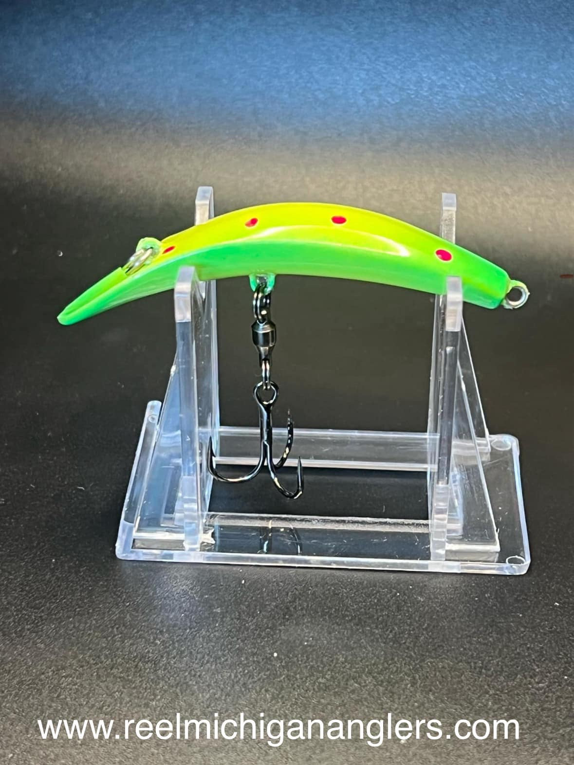Fin Diesel UV Swiftfish lure neon green with red dots, treble hooks on clear stand