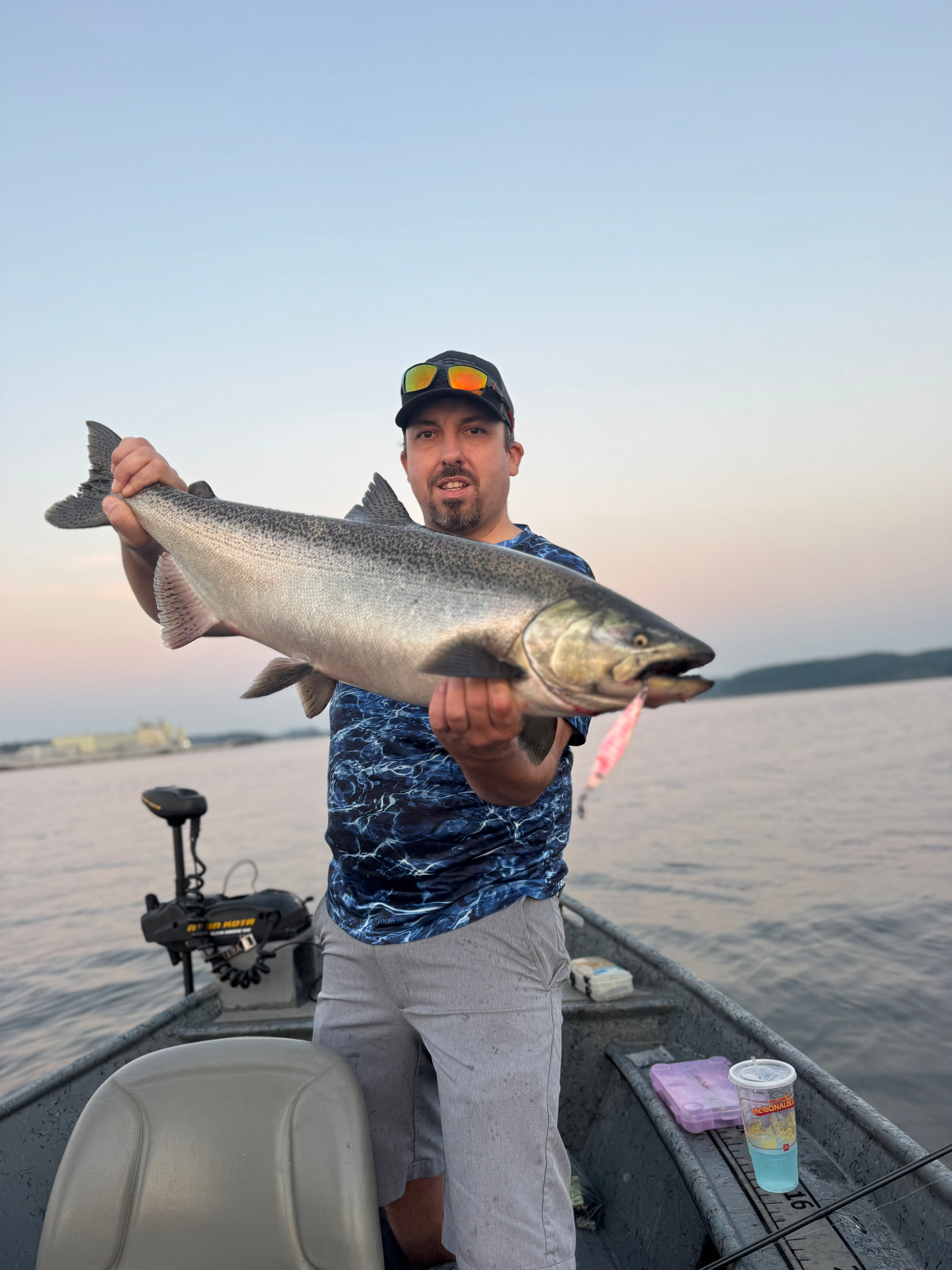 Pink UV jigging spoon with treble hooks, visible near fish mouth