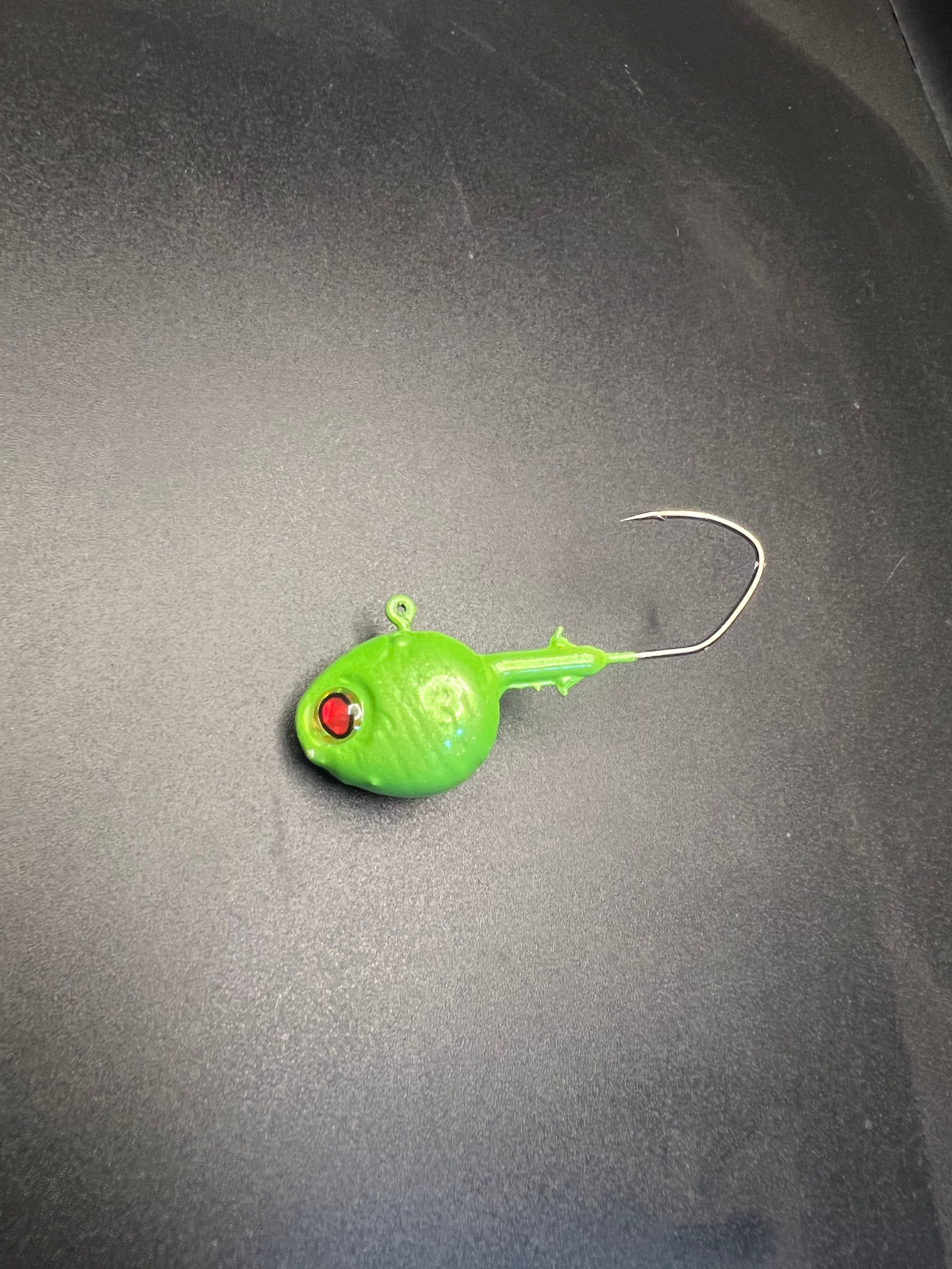 Green walleye jig with red eye, round head and curved metal hook
