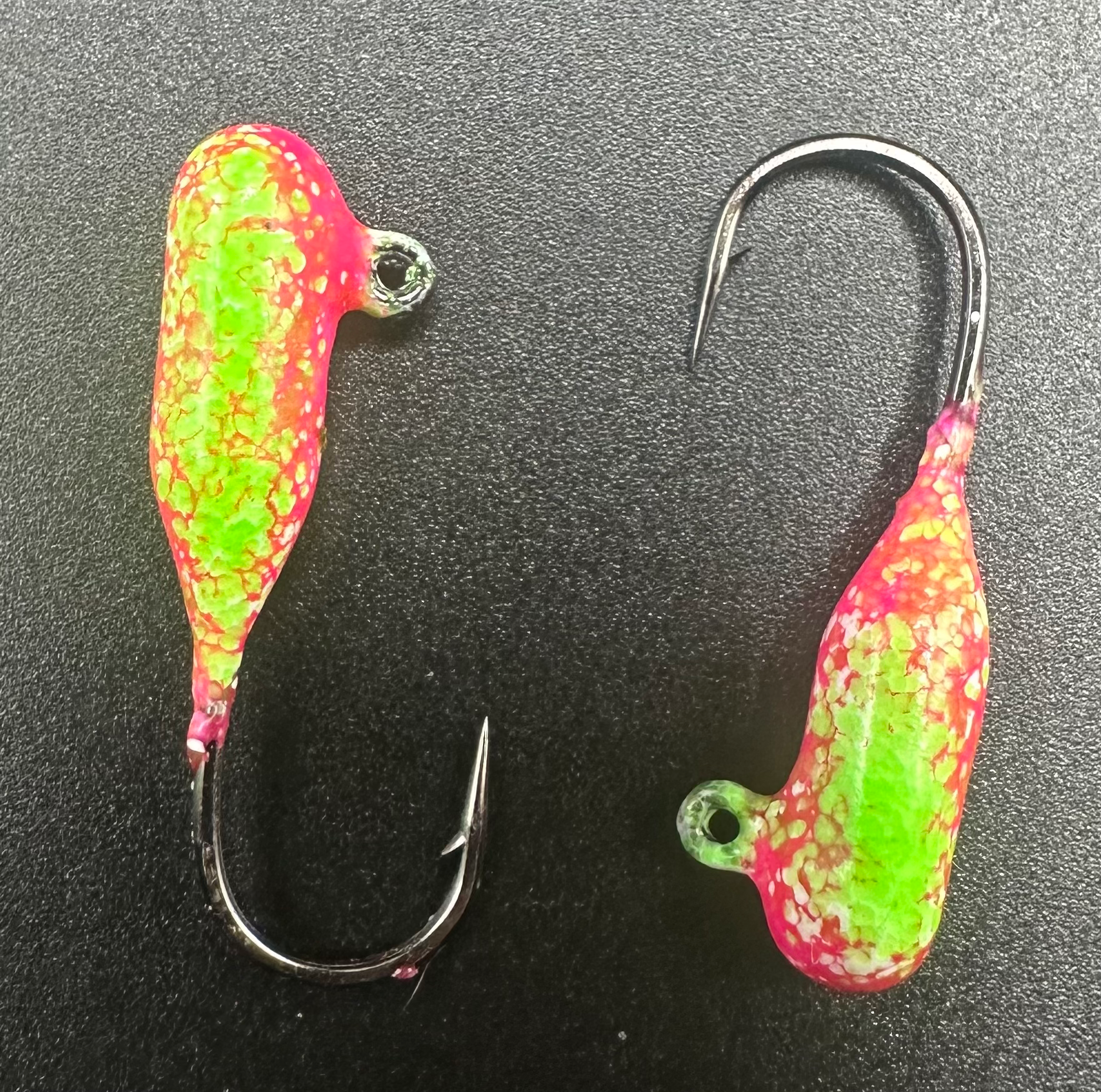 Pair of pink-and-green speckled tube jigs with black hooks and barbed points