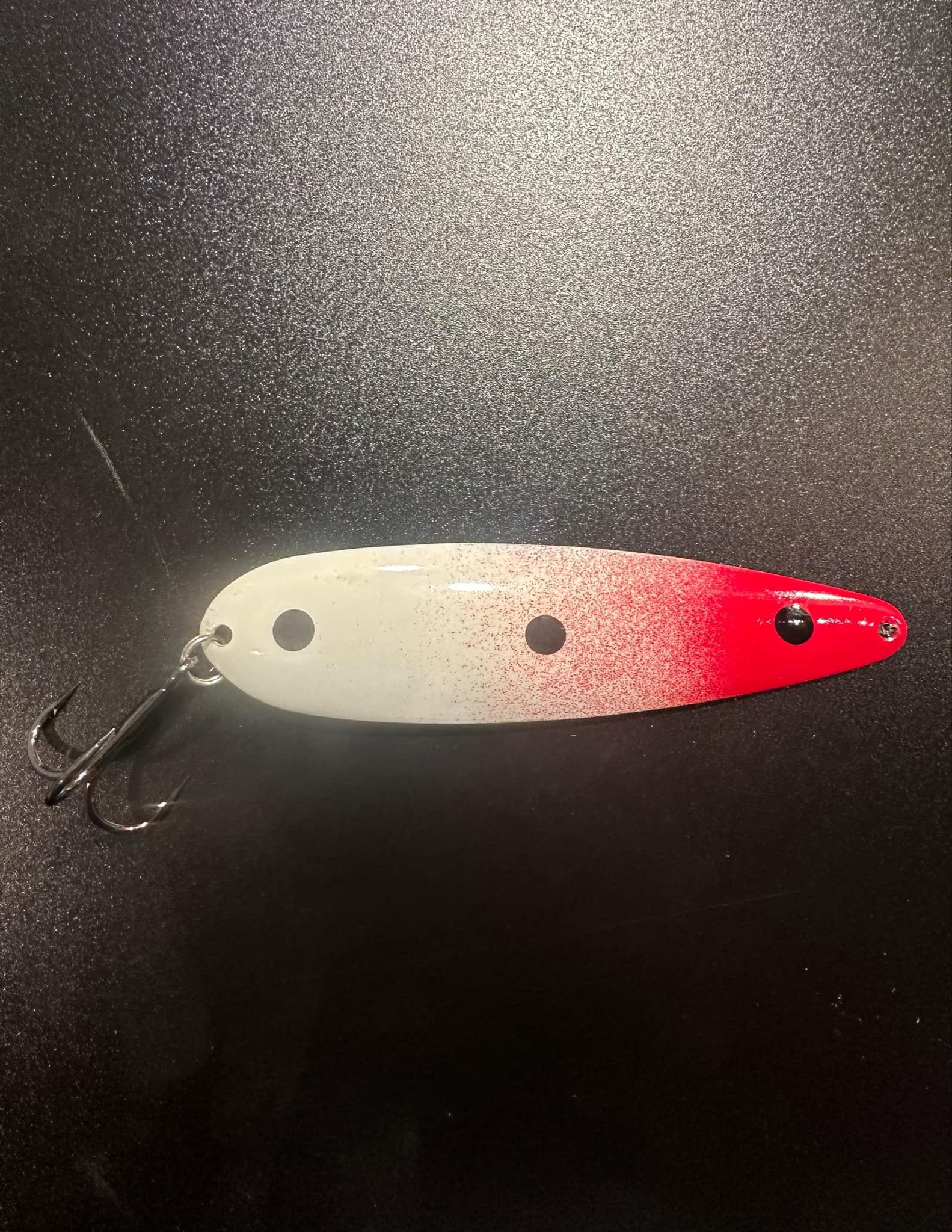 Red-and-white trolling spoon lure with black dot eyes and treble hooks