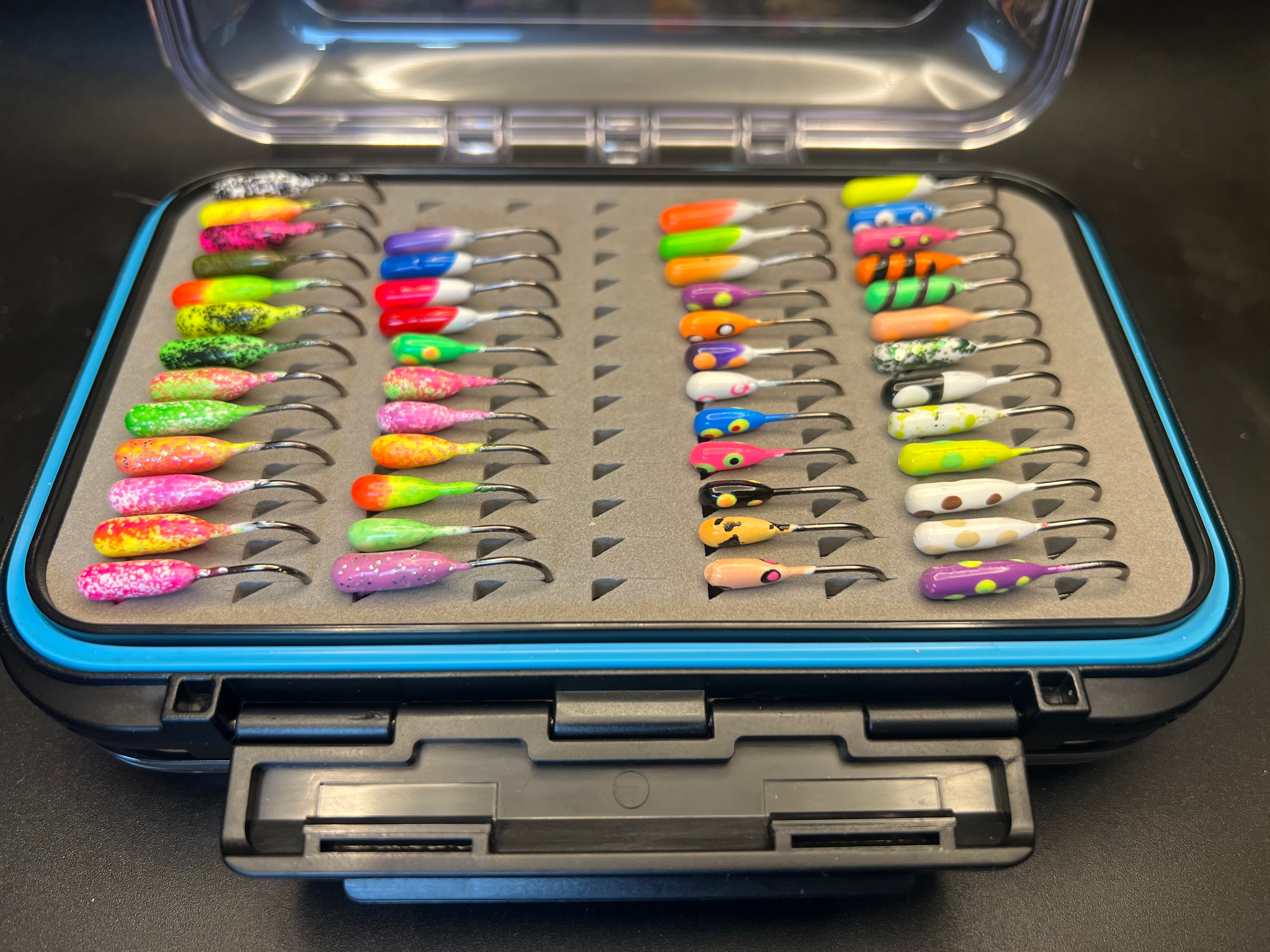 Top view of open double-sided jig box tray with multi-color tube jigs and hooks