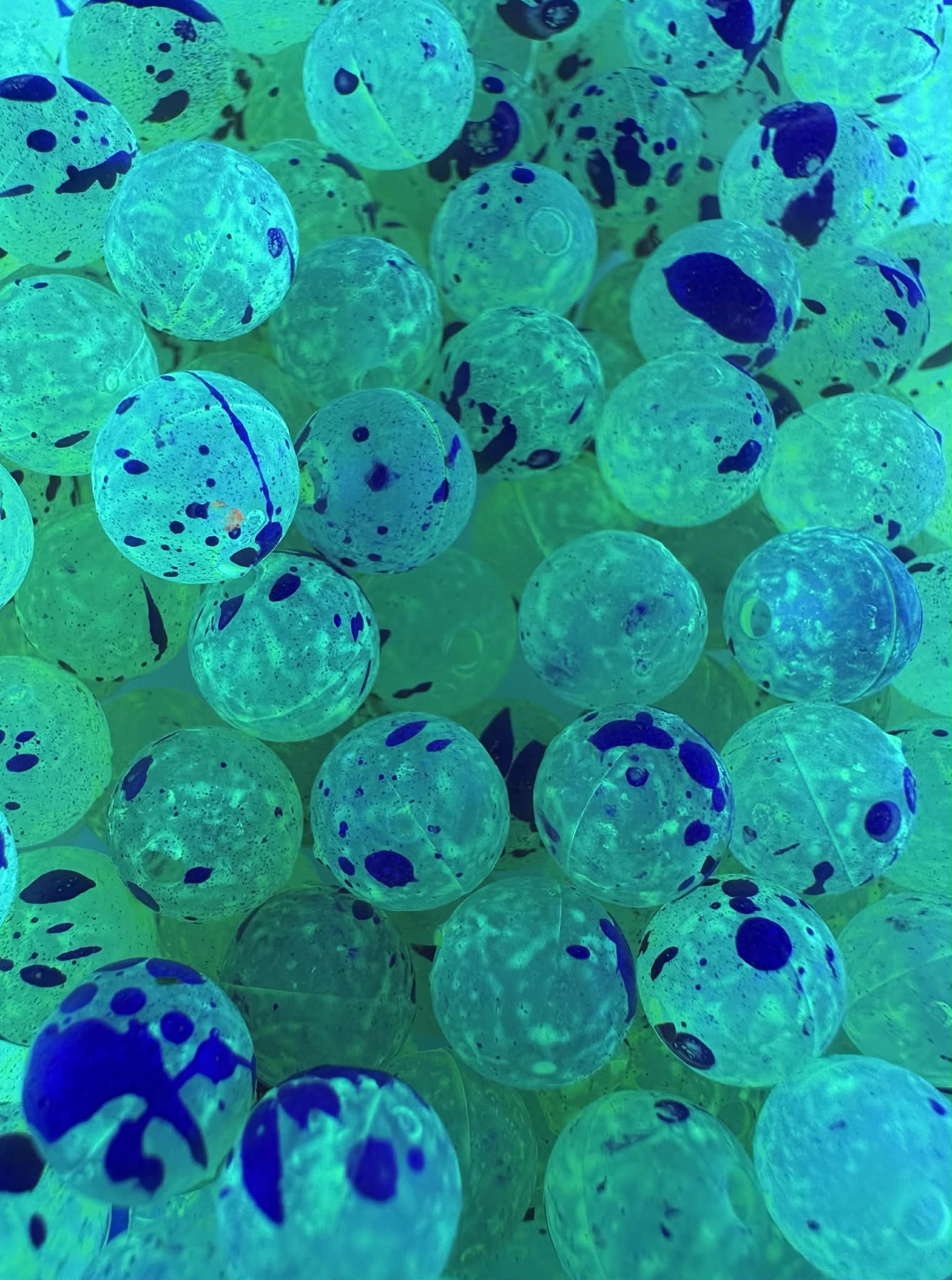 UV Glow fishing beads in green-blue with dark ink splatters