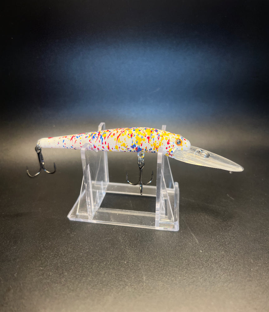 Multicolor fishing lure with UV glow body and two treble hooks on acrylic stand