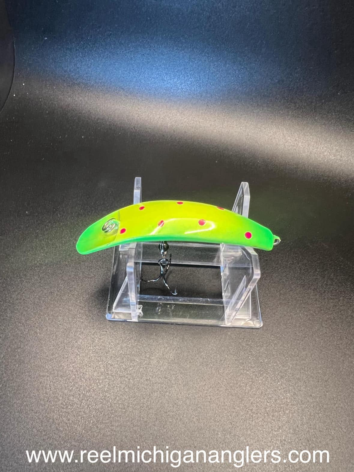 Fin Diesel UV Swiftfish lure neon green with red spots, side view on clear stand